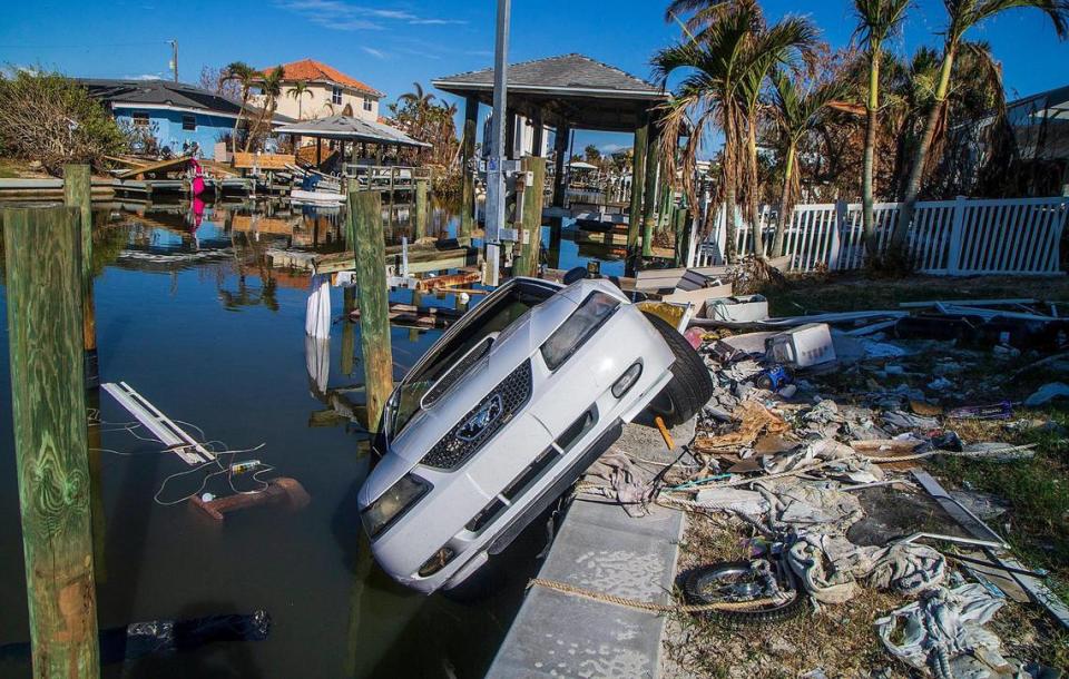 Un Ford Mustang de 2003 cuelga de un dique detrás de una casa de Estero Boulevard en Fort Myers Beach, el miércoles 26 de octubre de 2022. El coche fue arrastrado por la marea de tormenta del huracán Ian un mes antes.