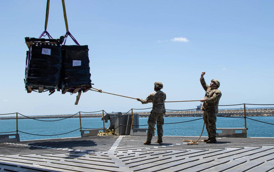 U.S. Army soldiers assigned to the 7th Transportation Brigade (Expeditionary) use a rope to stabilize humanitarian aid while it is lifted by a crane aboard the MV Roy P. Benavidez to support the Joint Logistics Over-the-shore (JLOTS) operation, in the Port of Ashdod, Israel, May 13, 2024. (Staff Sgt. Malcolm Cohens-Ashley/U.S. Army via AP)
