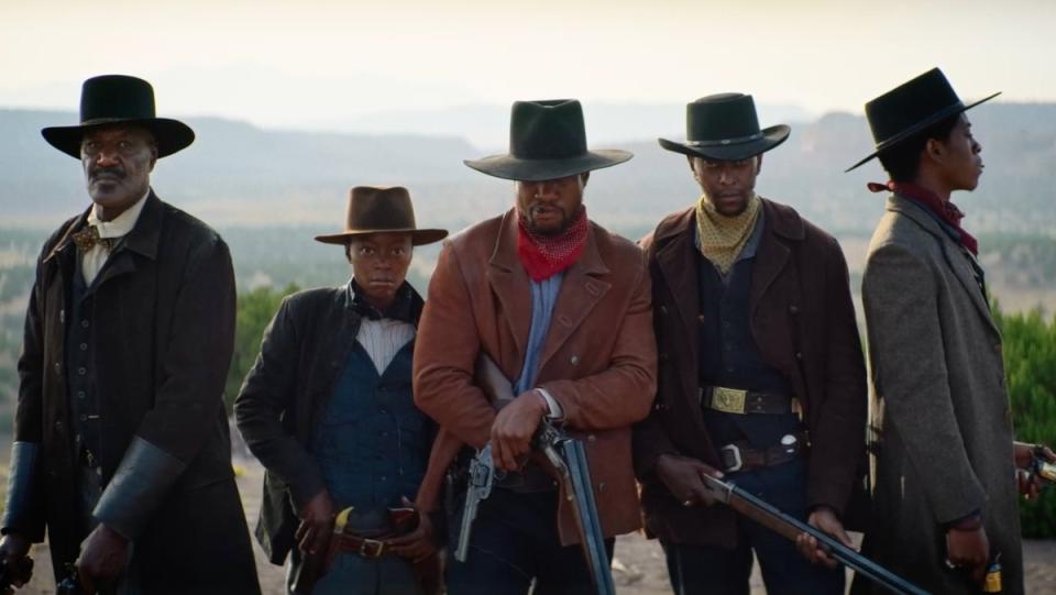 Photo of several Black cowboys standing in a line with hands on their guns in The Harder They Fall