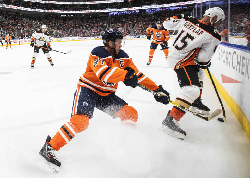 Anaheim Ducks' Ryan Getzlaf (15) and Edmonton Oilers' Connor McDavid (97) compete for the puck during the second period of an NHL hockey game Tuesday, Oct. 19, 2021, in Edmonton, Alberta. (Jason Franson/The Canadian Press via AP)