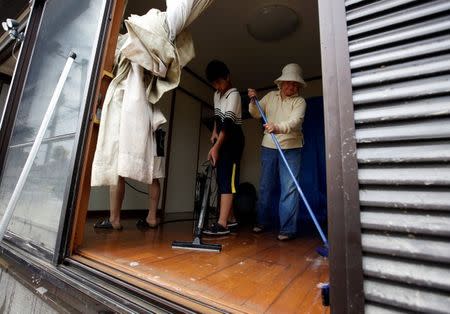 Family members of 79-year-old local resident Isao Akutagawa (not pictured), try to remove mud and debris from their house in a flood affected area in Mabi town in Kurashiki, Okayama Prefecture, Japan, July 12, 2018. Picture taken July 12, 2018. REUTERS/Issei Kato