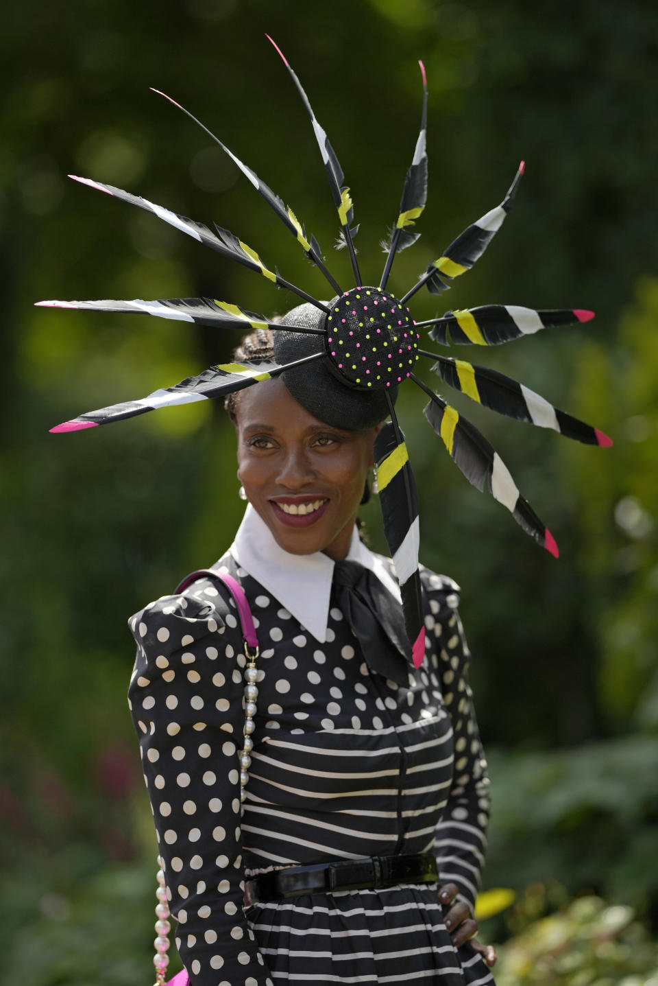 A racegoer smiles as she poses for a photo on the third day of the Royal Ascot horserace meeting, at Ascot Racecourse, in Ascot, England, Thursday, June 16, 2022. The third day is traditionally known as Ladies Day. (AP Photo/Alastair Grant)