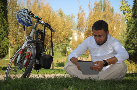Uzbek blogger Davronbek Tojialiyev looks at his tablet during an interview with Reuters in Tashkent, Uzbekistan October 2, 2018. REUTERS/Mukhammadsharif Mamatkulov/Files
