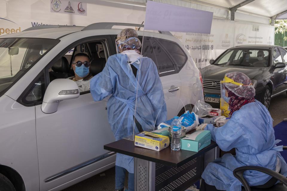 FILE - In this June 17, 2020 file photo, a health worker prepares to take swab samples to test for the coronavirus at a drive-through screening center in Cairo, Egypt. The coronavirus pandemic will exact a heavy toll on Arab countries, causing an economic contraction of 5.7% this year, pushing millions into poverty and compounding the suffering of those affected by armed conflict, a U.N. report said Thursday, July 23, 2020. The U.N.'s Economic and Social Commission for Western Asia expects some Arab economies to shrink by up to 13%, amounting to an overall loss for the region of $152 billion. (AP Photo/Nariman El-Mofty, File)