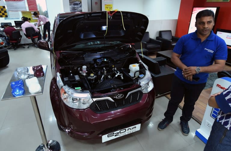 A sales executive talks about Mahindra's electric car "e2o Plus", on display at a showroom in New Delhi