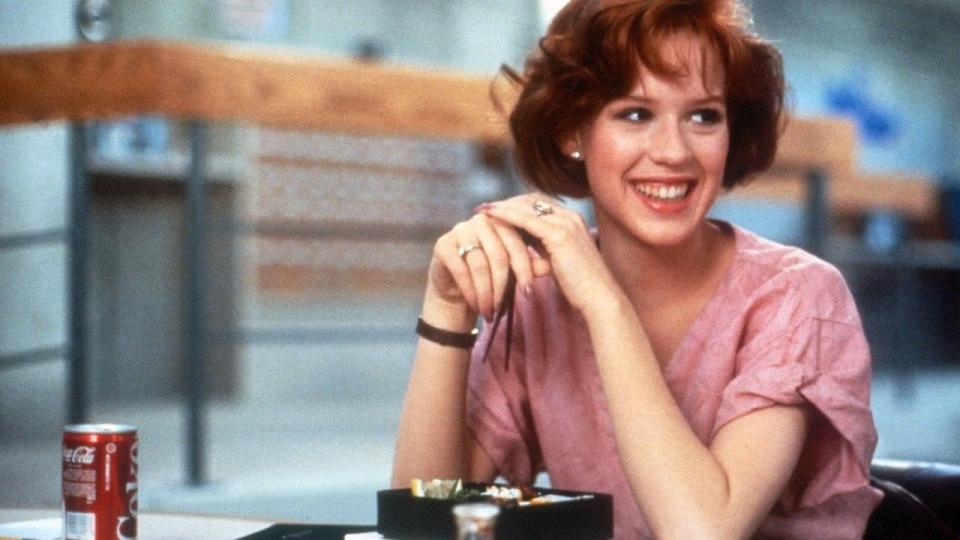 Molly Ringwald's character smiling while eating food