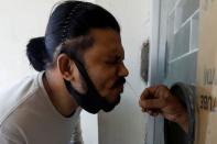 A man reacts as a paramedic takes a swab sample, to be tested for the coronavirus disease (COVID-19), from a window at the School of Nursing in Jinnah Postgraduate Medical Centre (JPMC) in Karachi