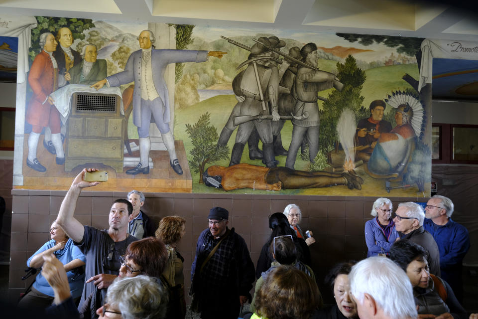 FILE - In this Aug. 1, 2019, file photo, people fill the main entryway of George Washington High School to view the controversial 13-panel, 1,600-square foot mural, the "Life of Washington," during an open house for the public in San Francisco. The San Francisco school board has voted to remove the names of George Washington and Abraham Lincoln from public schools after officials deemed them and other prominent figures, including Sen. Dianne Feinstein unworthy of the honor. After months of controversy, the board voted 6-1 Tuesday, Jan. 26, 2021, in favor of renaming 44 San Francisco school sites with new names with no connection to slavery, oppression, racism or similar criteria, the San Francisco Chronicle reported. (AP Photo/Eric Risberg, File)