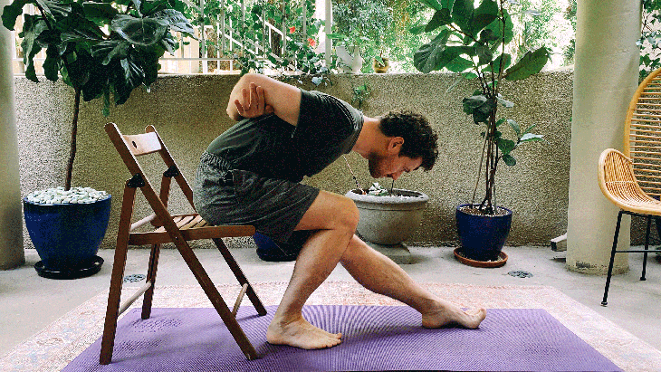 Man sitting on a chair practicing Pyramid Pose in yoga
