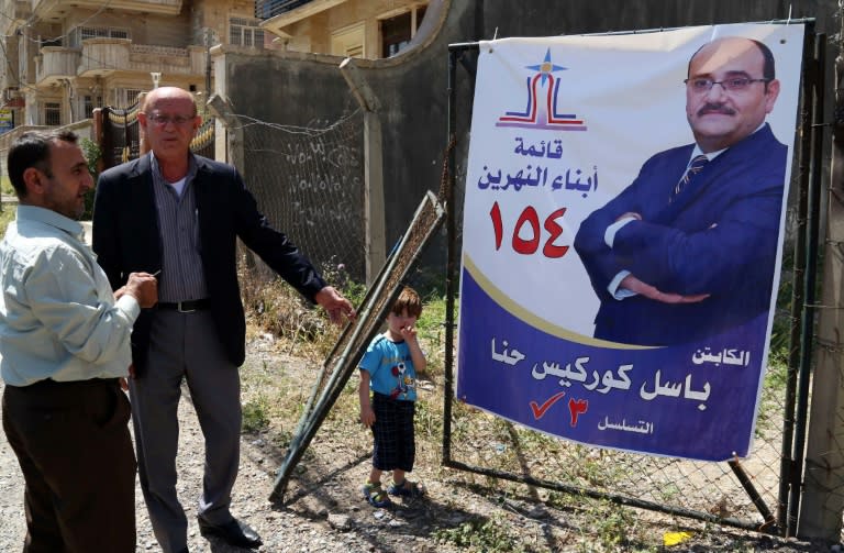 Men look at a campaign poster of Basil Gorgis, a former Iraqi footballer, in a street in Arbil, the capital of the northern Iraqi Kurdish autonomous region