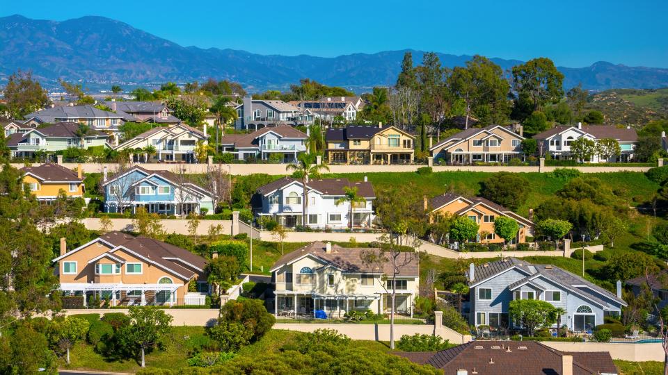 A hillside with many houses in Irvine in southern Orange County, California, with mountains in the background.