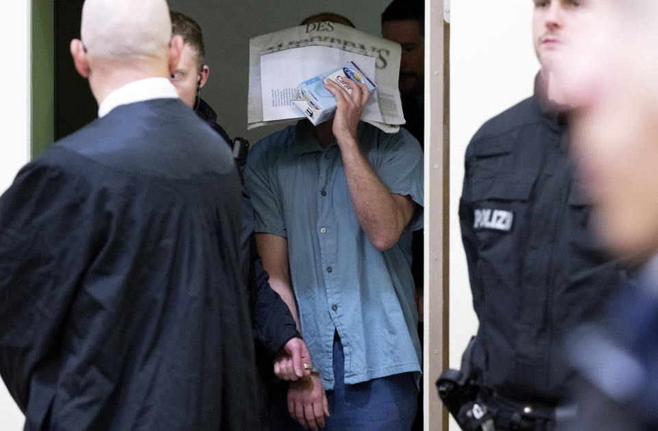 A man charged with membership of a terrorist organization and the preparation of a so-called high treasonous enterprise is led into the courtroom at the Higher Regional Court in Munich, Germany, Tuesday June 18, 2024. The third nationwide trial against suspected "Reich Citizens" of the group around Heinrich XIII Prince Reuss begins at the Munich Higher Regional Court (OLG). Eight suspected members of the group are to be tried in Munich. (Sven Hoppe/dpa via AP)