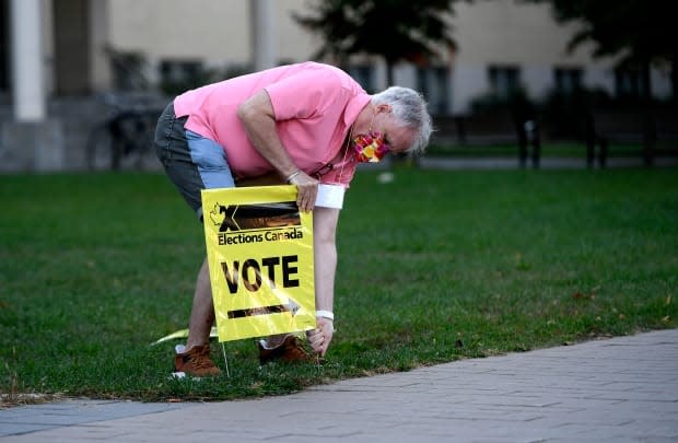 An Elections Canada officer plants a sign directing voters to a polling location in Ottawa on Sept. 20, 2021. (Justin Tang/Canadian Press - image credit)