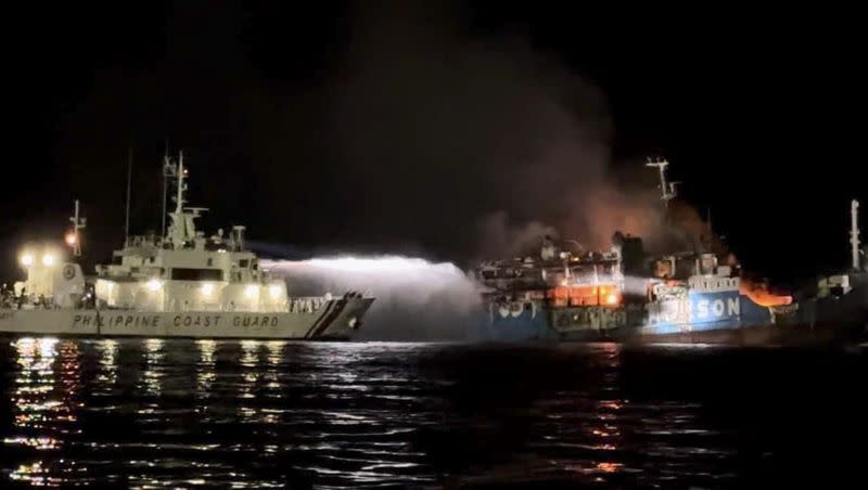 In this photo provided by the Philippine Coast Guard, a Philippine Coast Guard ship trains its hose as it tries to extinguish fire on the MV Lady Mary Joy at Basilan, southern Philippines early Thursday March 30, 2023. Multiple people died and others were missing after an inter-island cargo and passenger ferry with more than 200 passengers and crew onboard caught fire close to midnight in the southern Philippines, a provincial governor said Thursday. 
