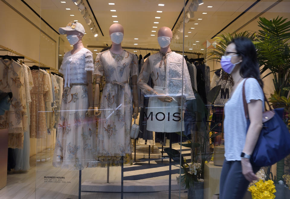 A woman wearing face mask walks at fashion shop at a downtown street in Hong Kong Sunday, May 31, 2020. (AP Photo/Vincent Yu)