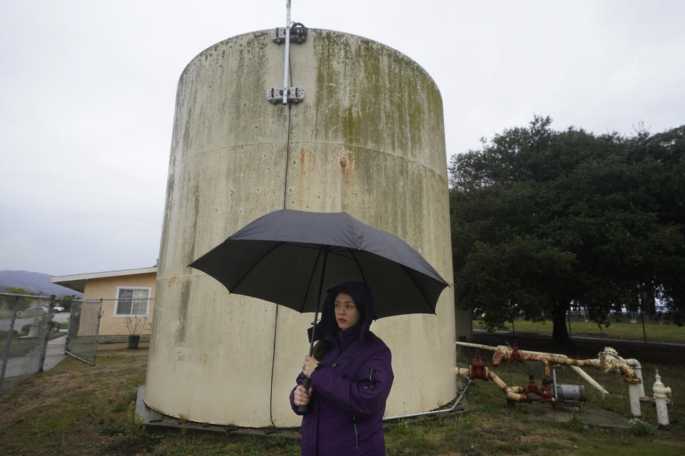 Ileana Miranda is interviewed in front of an old San Jerardo cooperative water tank in Salinas, Calif., Wednesday, Dec. 20, 2023. Some California farming communities have been plagued for years by problems with their drinking water due to nitrates and other contaminants in the groundwater that feeds their wells. (AP Photo/Jeff Chiu)