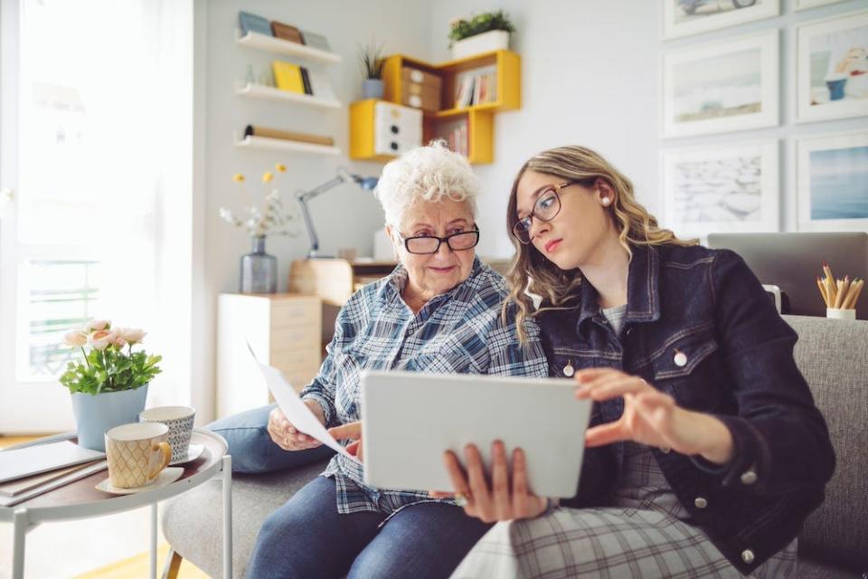 stock image of older woman and young person looking at computer and paperwork
