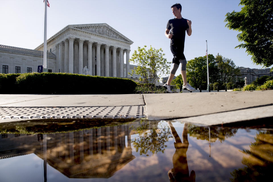 A man runs past the Supreme Court where the justices held arguments by telephone for the first time ever Monday. (AP Photo/Andrew Harnik