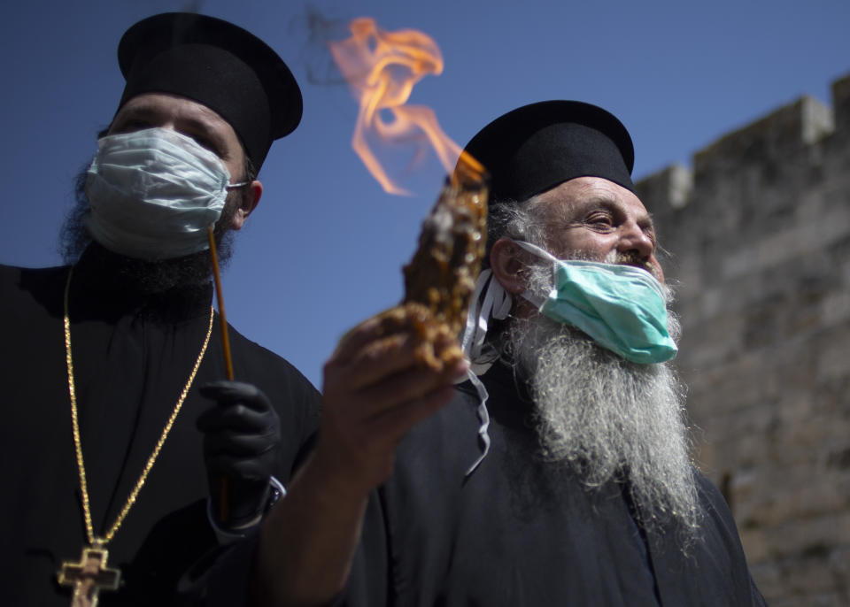 An Orthodox clergyman holds holy fire to transfer to predominantly Orthodox countries from the Church of the Holy Sepulchre, traditionally believed by many Christians to be the site of the crucifixion and burial of Jesus Christ, in Jerusalem's old city after the traditional Holy Fire ceremony was called off amid coronavirus, Saturday, April 18, 2020. A few clergymen on Saturday marked the Holy Fire ceremony as the coronavirus pandemic prevented thousands of Orthodox Christians from participating in one of their most ancient and mysterious rituals at the Jerusalem church marking the site of Jesus' tomb.(AP Photo/Ariel Schalit)