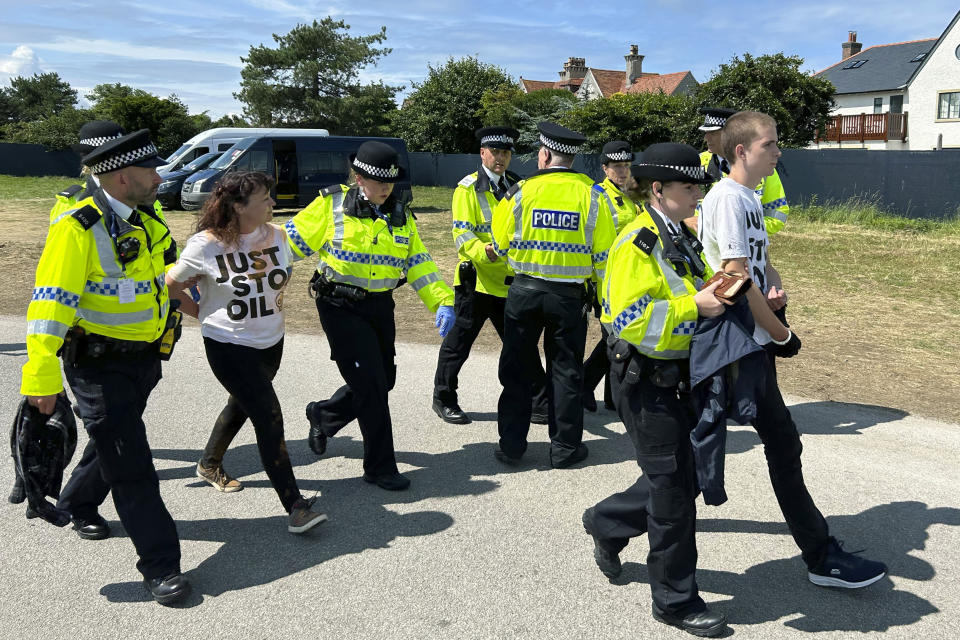 Just Stop Oil protesters are led away from the 17th green by police and security where they had thrown material onto the course, during the second day of the British Open Golf Championships at the Royal Liverpool Golf Club in Hoylake, England, Friday, July 21, 2023. (AP Photo)