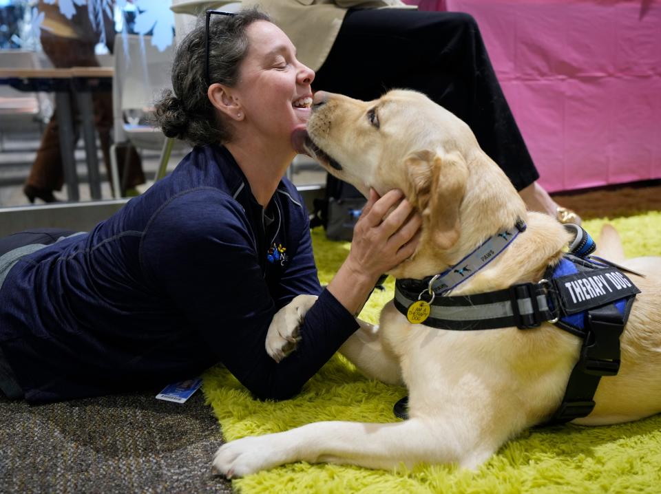 Danielle Barber, a researcher with Nationwide Children's Hospital, trades affection with Butterfly Paws therapy dog Sadie on Tuesday during an event held by Nationwide Children's Hospital to announce the establishment of the Kids Mental Health Foundation.