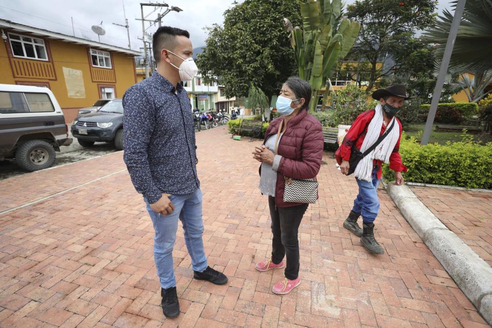 Wearing masks to curb the spread of the new coronavirus, Mayor Jaime Rodriguez, left, talks with a resident in Campohermoso, Colombia, Thursday, March 18, 2021. Rodriguez has been the only town resident to contract COVID-19 when he travelled to the Capital of Colombia, Bogota, but he had to stay there until he recovered to avoid spreading the disease in his home town. (AP Photo/Fernando Vergara)