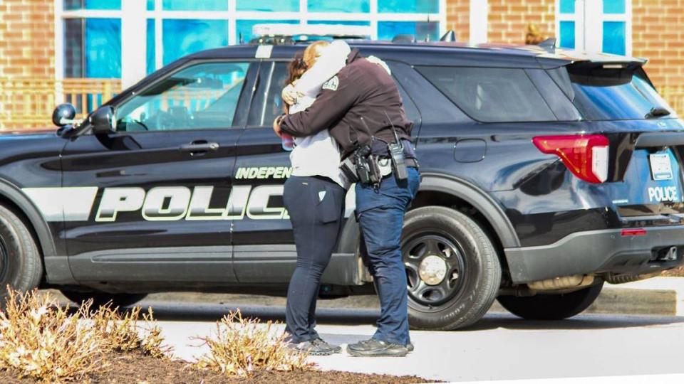 An unidentified woman and unidentified law enforcement officer embrace outside Centerpoint Medical Center in Independence Thursday after an Independence police officer and court process server died in a shooting incident in eastern Independence . Multiple people injured in the incident were taken by ambulance to the hospital.