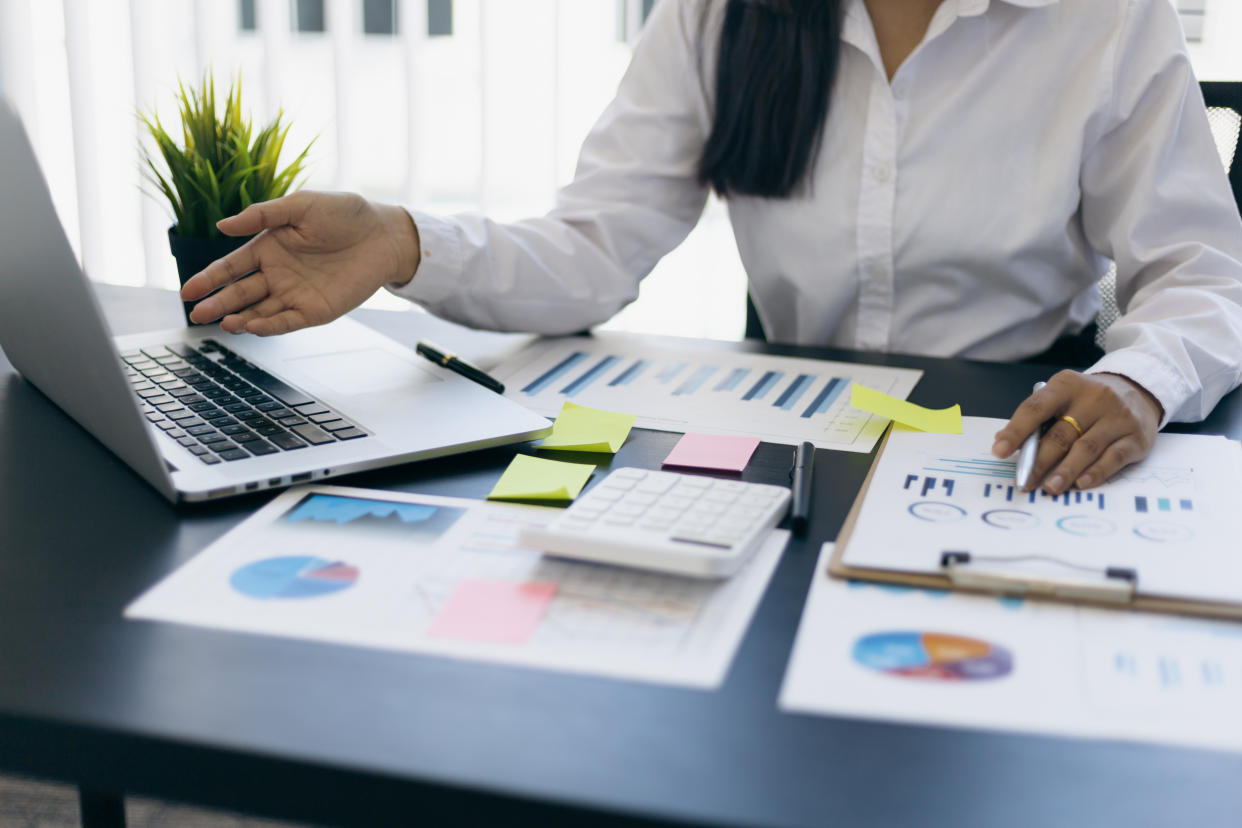 Businesswoman finance market analyst working on laptop pointing at business finance report chart document on desk in office. Finance and bookkeeping concepts using computer software.