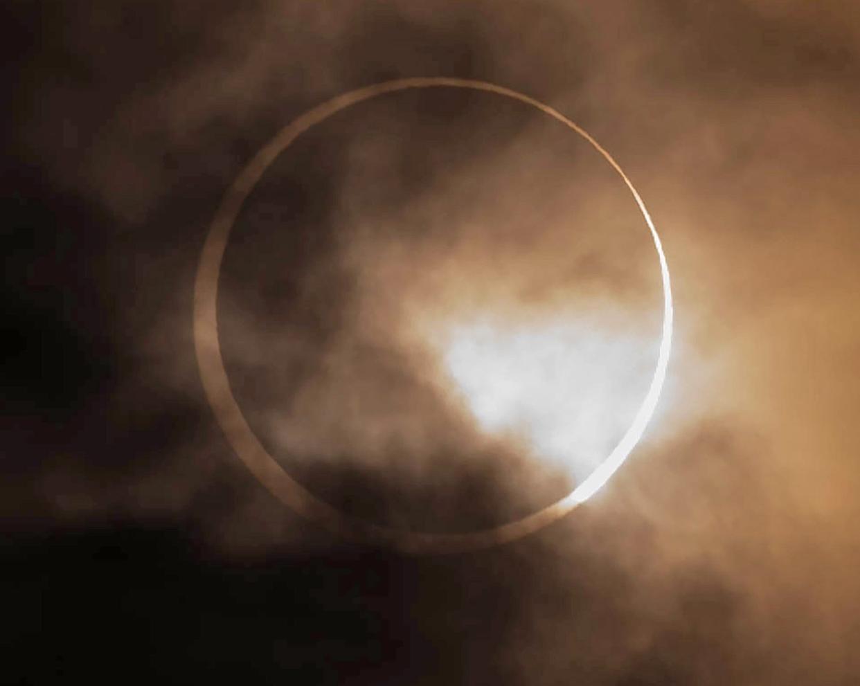 The annular eclipse peers though the clouds over Oregon from Skinner Butte in Eugene, Ore. Saturday, Oct. 14, 2023.