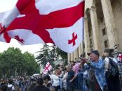 Opposition demonstrators wave a Georgian national flags as they gather in front of the Georgian Parliament building in Tbilisi, Georgia, Monday, June 24, 2019. Demonstrators have returned to parliament for daily rallies, demanding the release of detained protesters, the ouster of the nation's interior minister and changes in the electoral law to have legislators chosen fully proportionally rather than the current mix of party-list and single-mandate representatives. (AP Photo/Shakh Aivazov)