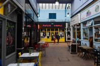 A couple walk past empty restaurants during a quiet night at Brixton Village in London