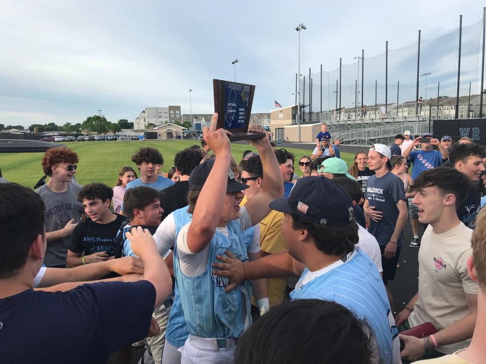 Waldwick senior Mike O'Neil hoists the North 1, Group 1 baseball championship trophy as fans and teammates surround him in the postgame celebration. Friday, June 10, 2022 at Wood-Ridge Athletic Complex.