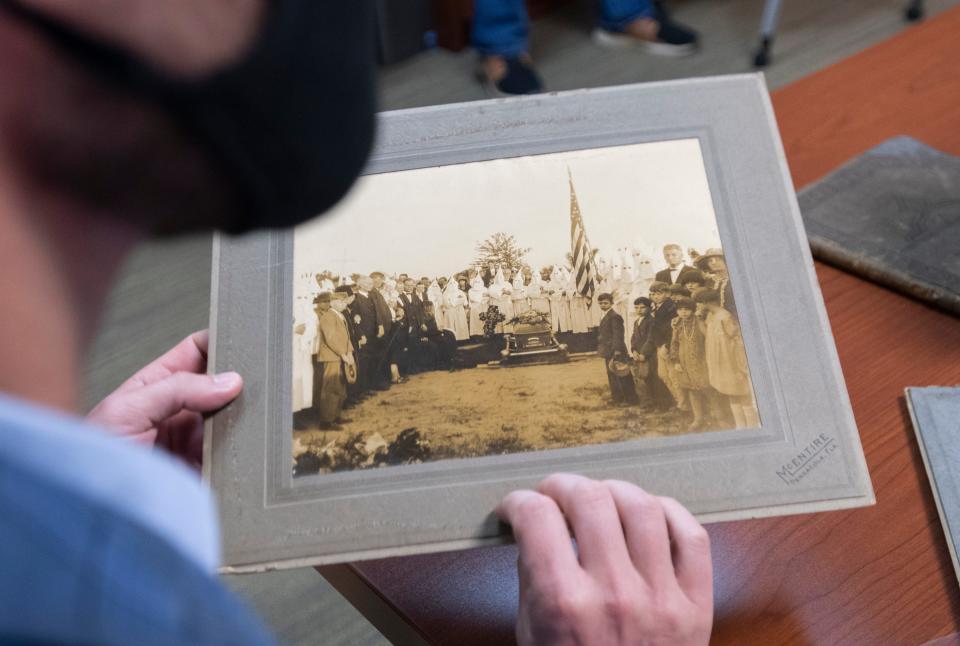 Jamin Wells, assistant professor and director of the Public History Master's Program at the University of West Florida, looks at a photograph July 20, 2020, as a UWF Historic Trust team catalogs Ku Klux Klan artifacts from T.T. Wentworth Jr. at the Voices of Pensacola Multicultural Center in downtown Pensacola.