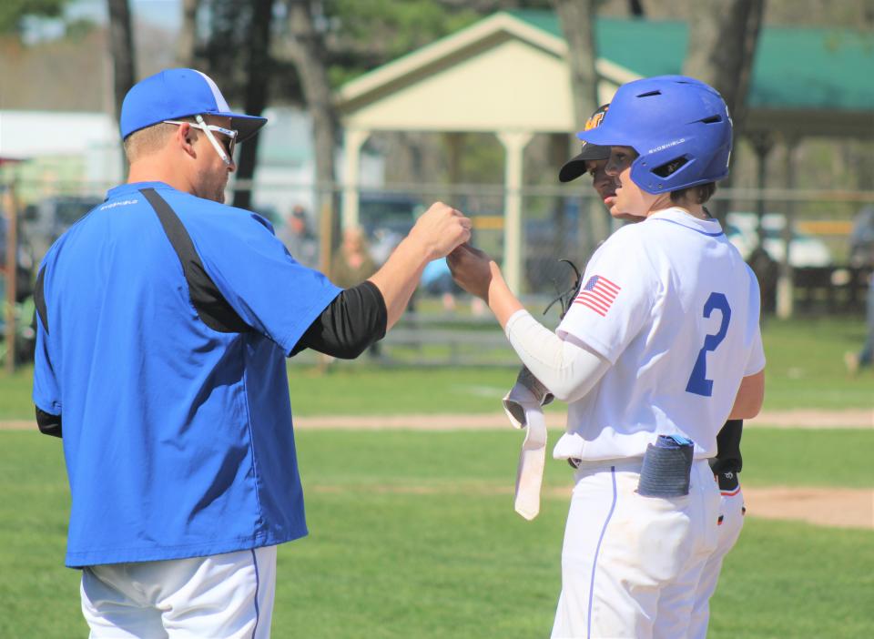 Inland Lakes sophomore Ty Kolly (2) gets congratulated by assistant coach Dusty Saker after reaching first base against Mancelona on Friday, May 10.