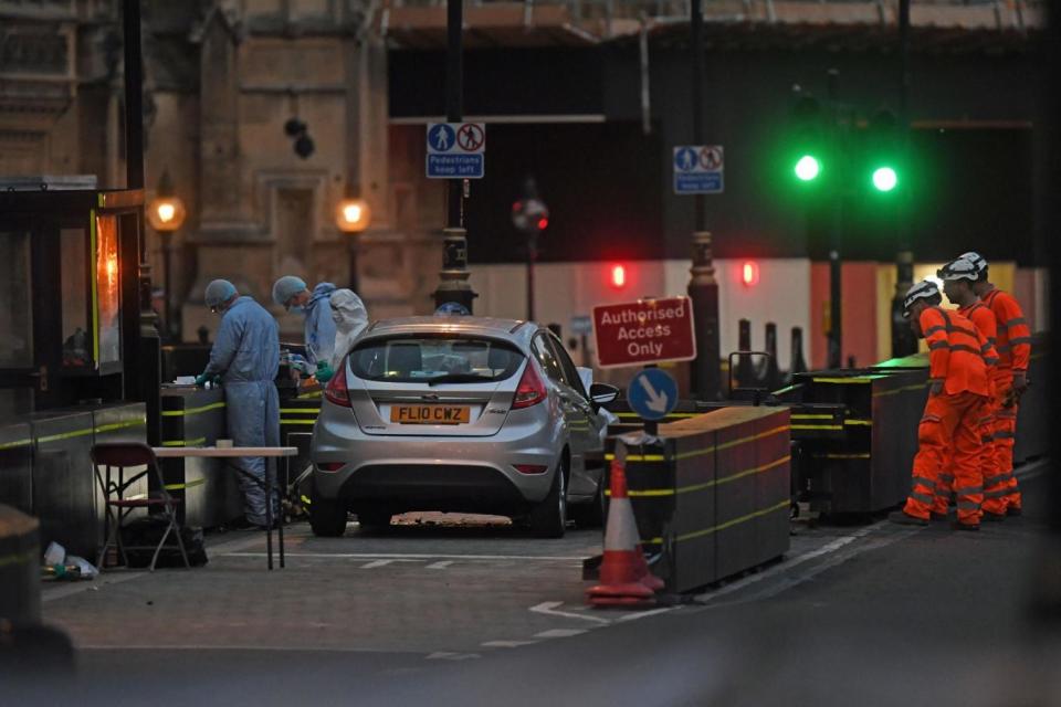 Forensic officers by the car that crashed into security barriers outside Parliament (PA)