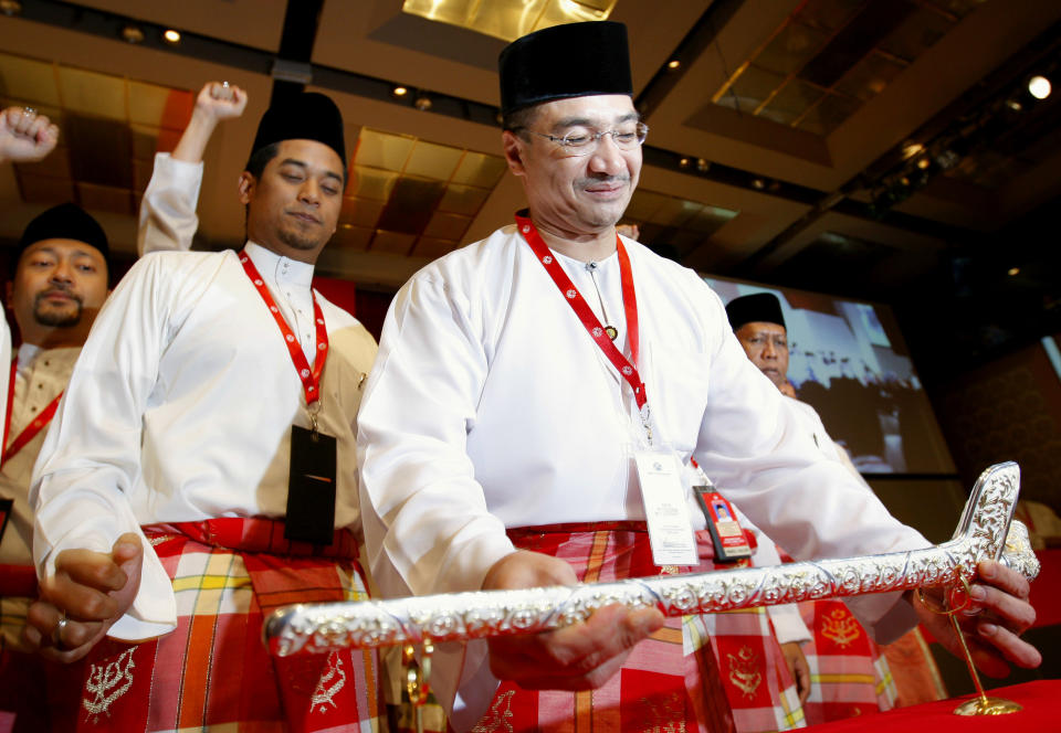 FILE - In this Wednesday, March 25, 2009 file photo, Hishammuddin Hussein, front, chief of Youth wings placing the "Malay Keris" on a ceremonial display stand during the opening of United Malays National Organisation (UMNO) Youth general assemblies in Kuala Lumpur, Malaysia. Hishammuddin Hussein’s wife is a princess. His cousin is prime minister, and he’s been mentioned as a possible successor. But right now, as the face of his country’s effort to find Malaysia Airlines Flight 370, he is the man who has delivered more than two weeks of frustrating news about one of the most confounding searches in aviation history. (AP Photo/Vincent Thian)