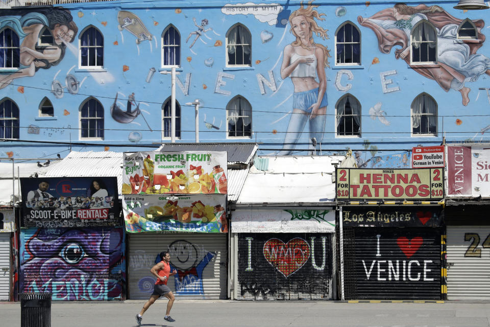 A man jogs in front of closed-off store fronts on March 29, 2020, in the Venice Beach section of Los Angeles. (Marcio Jose Sanchez/AP)