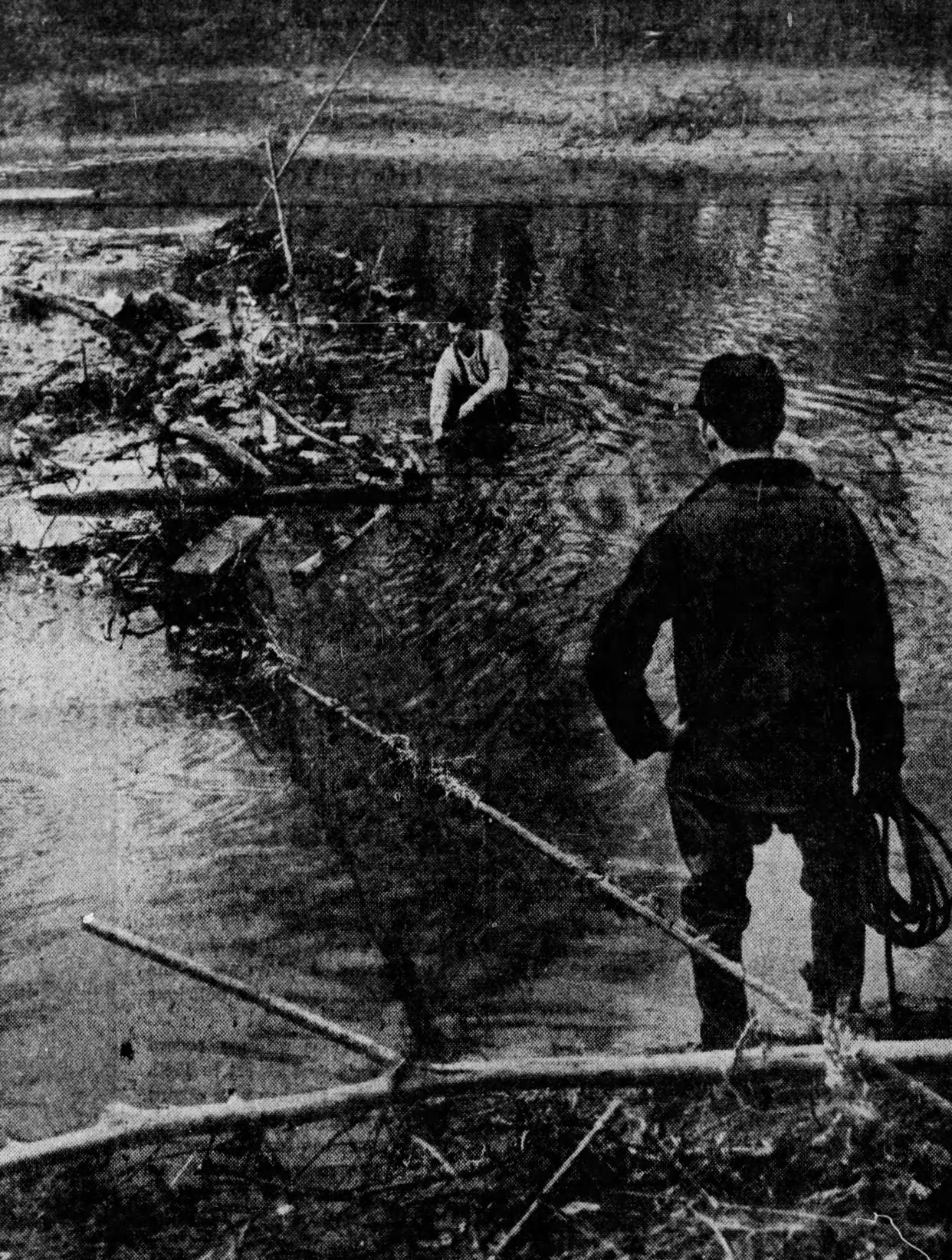 C.M. Davis stands along the Tuscarawas River near Canal Fulton while W.R. Miner searches the water for their friend Ercell Elizabeth Russell, 36, of Barberton, on Jan. 16, 1949. She disappeared Dec. 10, 1948, and her abandoned car was found two days later off Route 21.