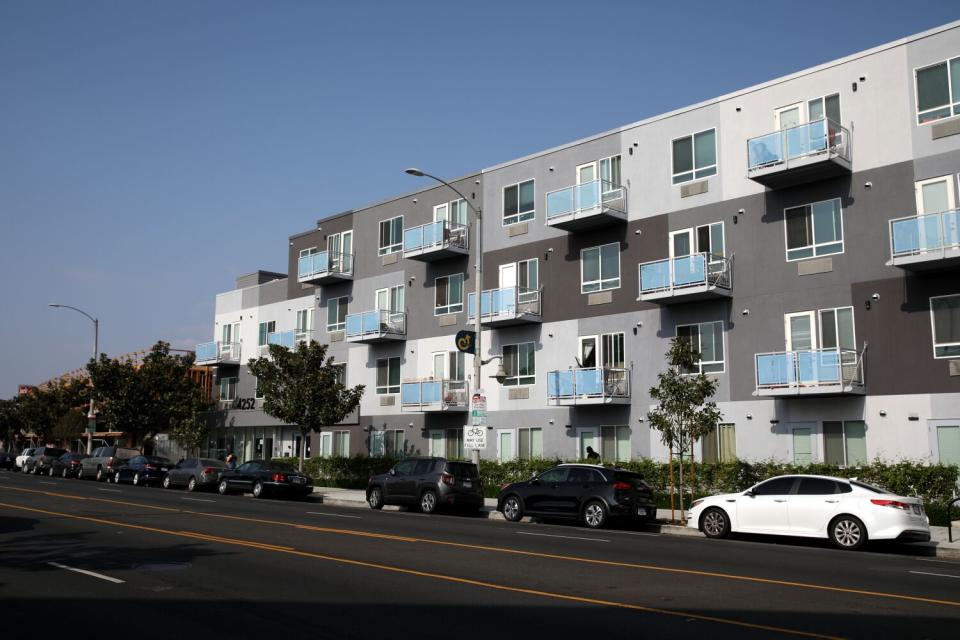 A large, modern apartment structure next to a road