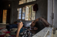 Police officers who fled Myanmar following a military coup rests at an undisclosed location bordering Myanmar, in the northeastern Indian state of Mizoram, Thursday, March 18, 2021. Villagers in Mizoram have given shelter to 34 Myanmar police personnel and 1 fire fighter, who crossed over to the state over the last two weeks. Those who escaped spend their time watching local television and doing daily chores. Some of them have carried mobile phones and are trying to connect to families they were forced to leave behind. At night, all of them go to sleep on mattresses laid on the floor of a single room. (AP Photo/Anupam Nath)