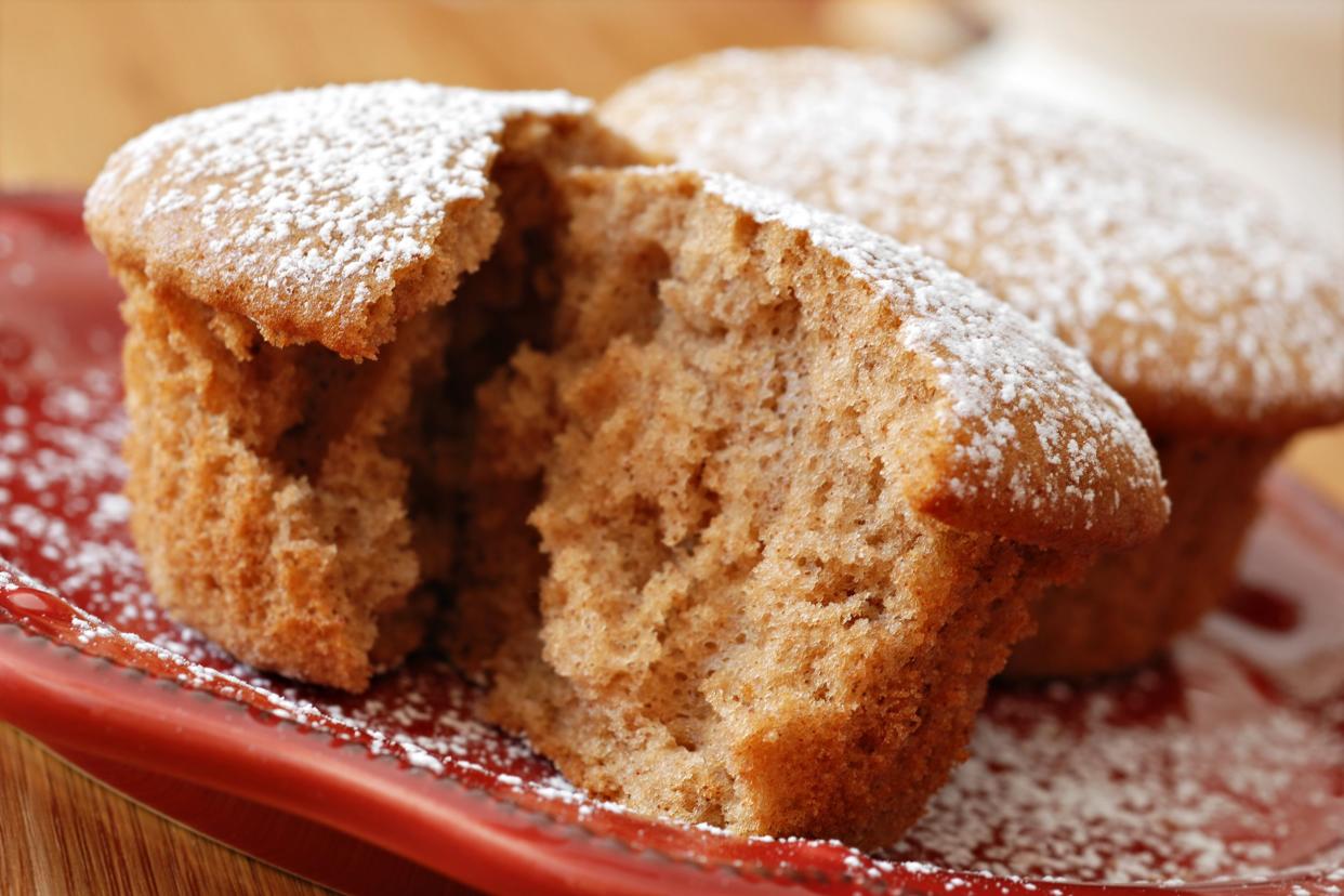 Closeup of two ginger spice cupcakes on a red plate decorated with powdered sugar on a table with the blurred background