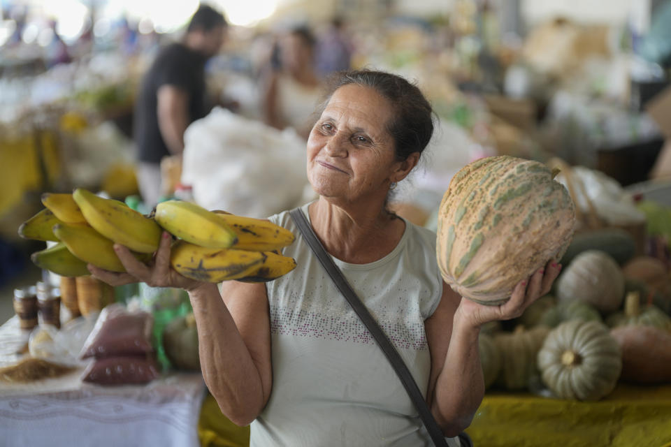 María do Carmo muestra los vegetales y frutas que vende en un puesto de una feria de Aracuai, en el estado brasileño de Minas Gerais, el 11 de octubre del 2022. Dice que las ventas aumentaron desde que el gobierno de Jair Bolsonaro dispuso nuevos beneficios para los pobres en la antesala de las elecciones presidenciales. (AP Photo/Andre Penner, File)