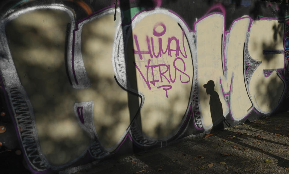 A man wearing a protective mask passes by a mural during a community quarantine to help curb the spread of the new coronavirus in Manila, Philippines on Wednesday, April 1, 2020. The new coronavirus causes mild or moderate symptoms for most people, but for some, especially older adults and people with existing health problems, it can cause more severe illness or death. (AP Photo/Aaron Favila)