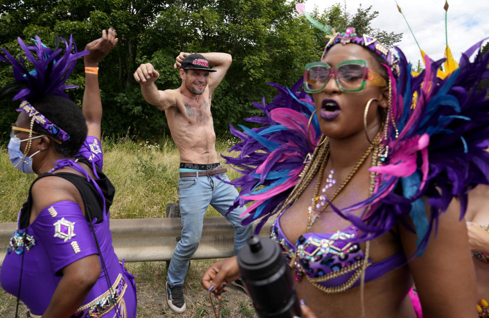 A homeless man dances as participants of the Caribbean Carnival parade parade by in Toronto, Canada, Saturday, July 30, 2022.The 55th annual parade returned to the streets after the COVID-19 pandemic cancelled it for two years in a row. (AP Photo/Kamran Jebreili)