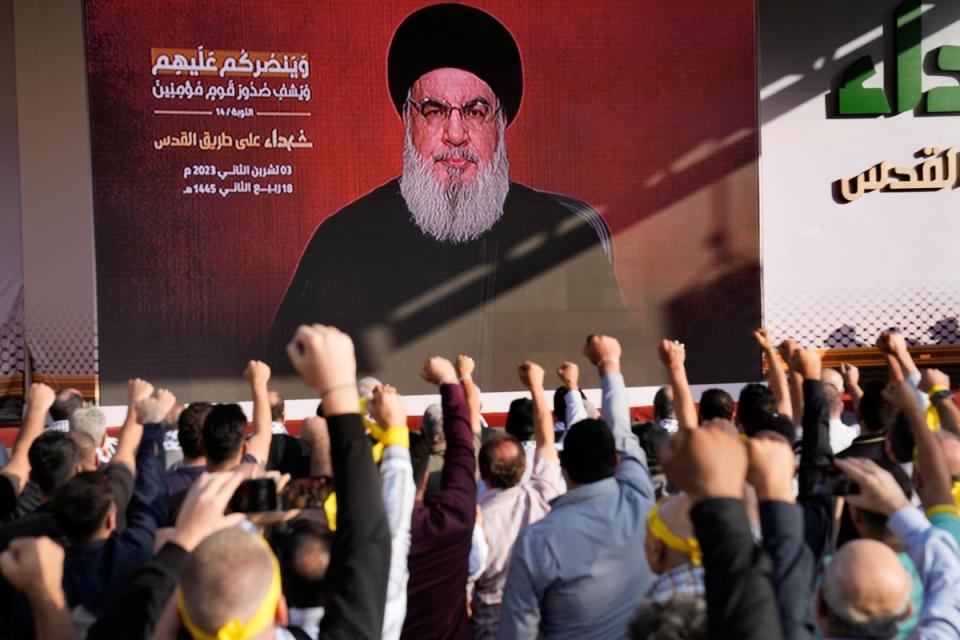 Supporters of the Iranian-backed Hezbollah group raise their fists and cheer as Hezbollah leader Sayyed Hassan Nasrallah appears via video link, during a rally to commemorate a Hezbollah fighter (Hussein Malla / AP)