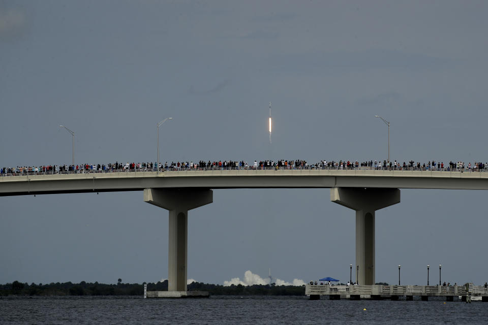 Spectators watch from a bridge in Titusville, Fla. as SpaceX Falcon 9 lifts off with NASA astronauts Doug Hurley and Bob Behnken in the Dragon crew capsule, Saturday, May 30, 2020 from the Kennedy Space Center at Cape Canaveral, Fla. The two astronauts are on the SpaceX test flight to the International Space Station. For the first time in nearly a decade, astronauts blasted towards orbit aboard an American rocket from American soil, a first for a private company. (AP Photo/Charlie Riedel)