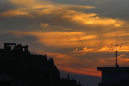 The ancient Greek temple of Erechtheion (L) atop the Acropolis hill is silhouetted against the sunset in Athens February 21, 2015. REUTERS/Yannis Behrakis