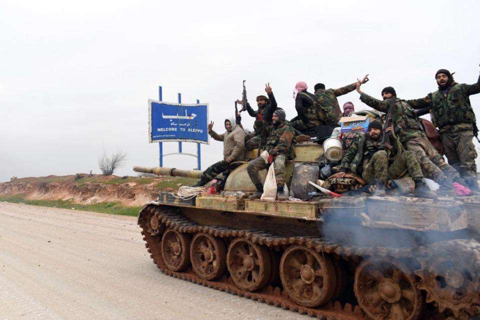 In this photo released Wednesday, Feb. 12, 2020, by the Syrian official news agency SANA, Syrian government soldiers on a tank hold up their rifles and flash victory signs, as they patrol the highway that links the capital Damascus with the northern city of Aleppo, Syria. The M5 highway, recaptured by President Bashar Assad’s forces this week, is arguably the most coveted prize in Syria’s civil war. The strategic highway is vital for Syria’s economy as well as for moving troops. (SANA via AP)