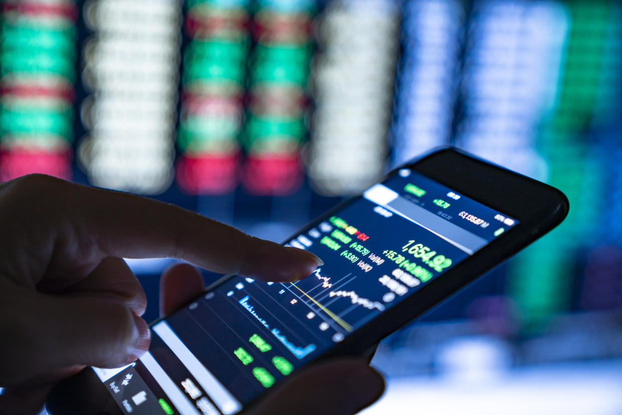 Close-up of hands of businesswoman looking at stock market charts and key performance indicators on her smartphone