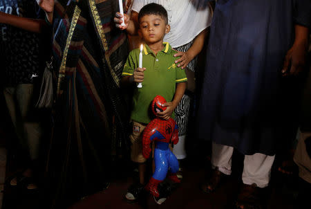 A boy holds an inflatable Spiderman as he attends a candle light vigil with others for the victims of the attack on the Holey Artisan Bakery and the O'Kitchen Restaurant, in Dhaka, Bangladesh, July 3, 2016. REUTERS/Adnan Abidi